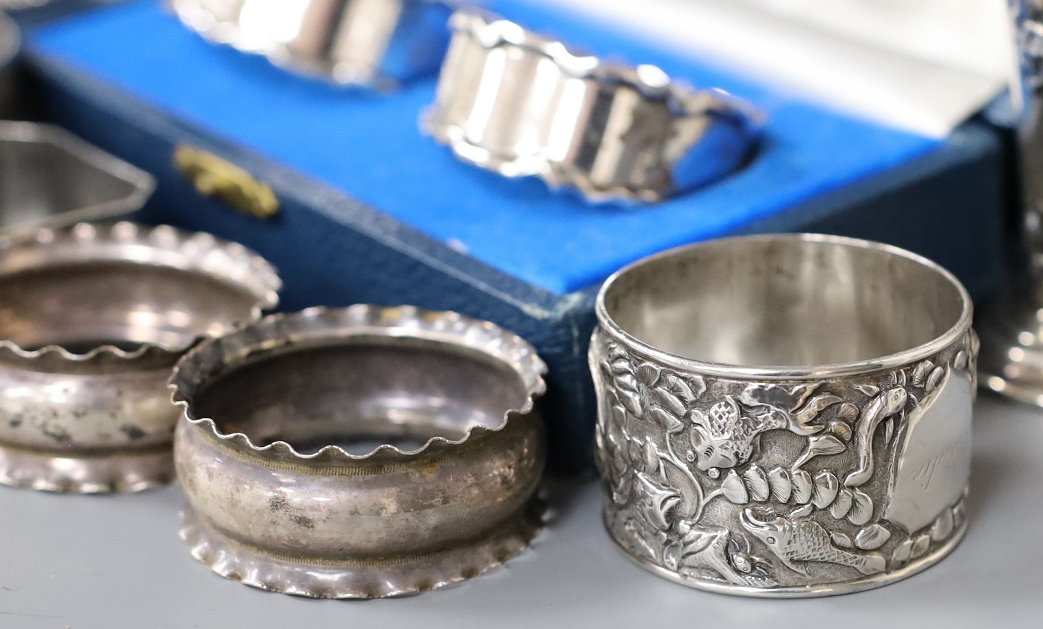 A cased pair of silver napkin rings, five others including one white metal and a two small silver vases, weighted.